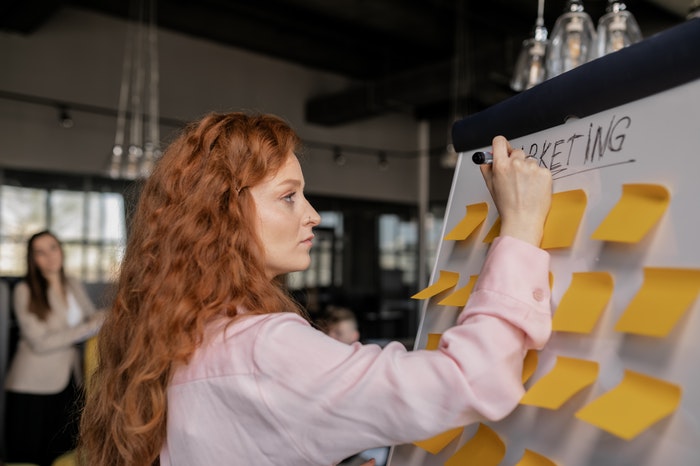woman writing about marketing on whiteboard